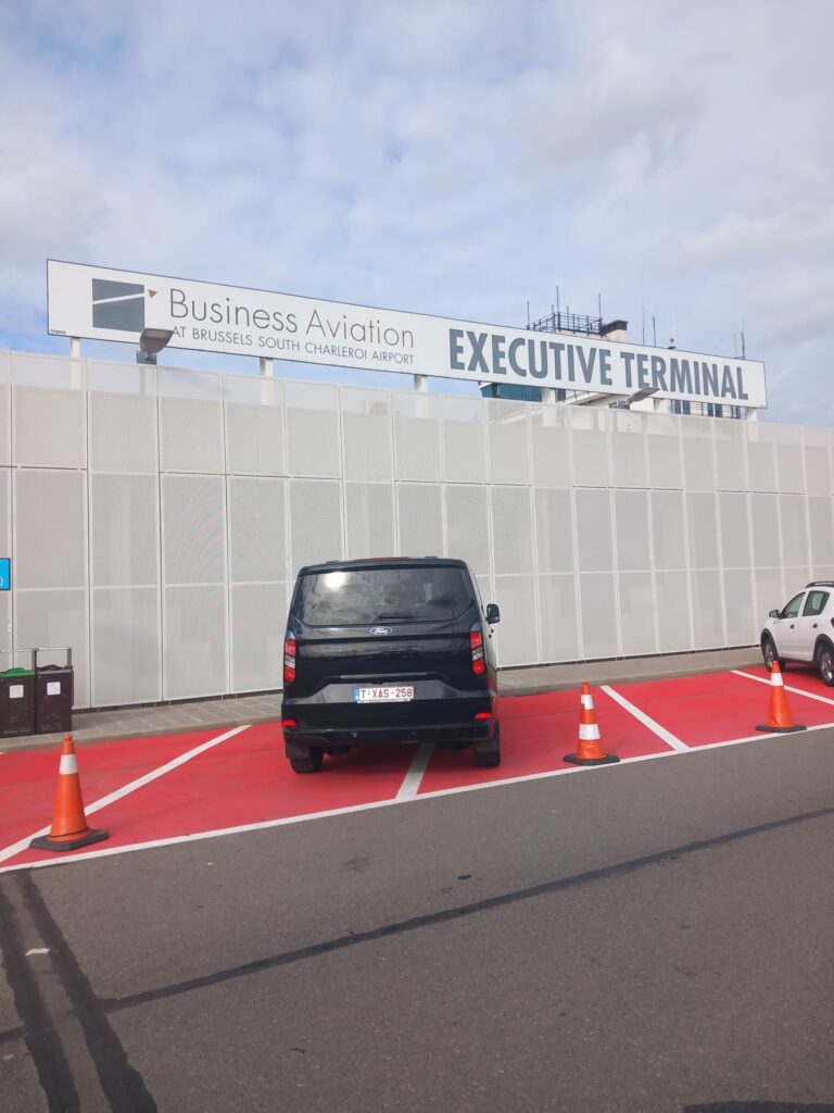 Minivan Taxi Namur stationné devant le terminal de l’aéroport pour la prise en charge